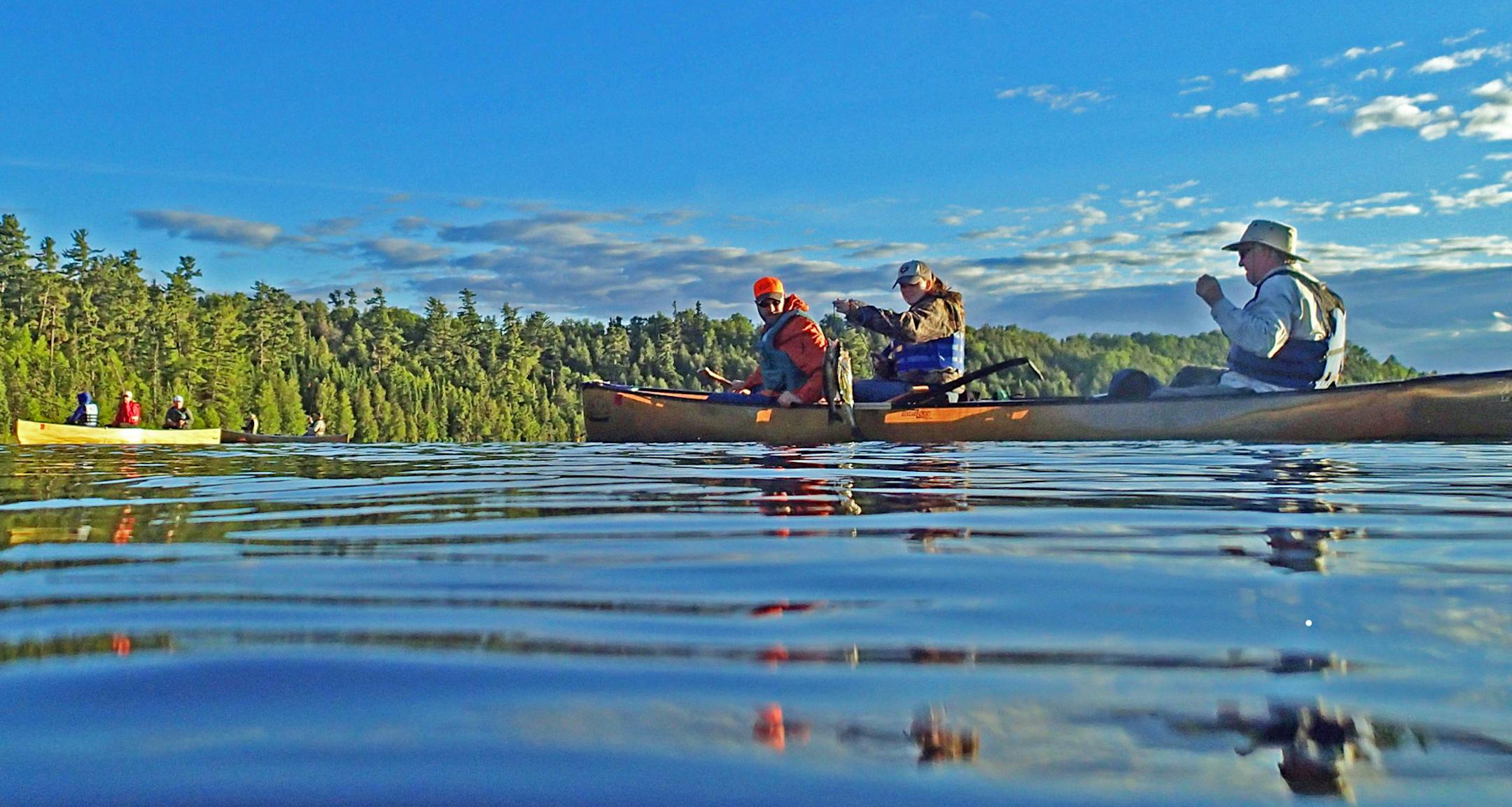 Robert Bjerken of Minneapolis, in the bow, and Tom Ellsworth of Excelsior in the stern, look on as Katie Ellsworth of Minneapolis holds up a stringer of walleyes taken Tuesday night in the Boundary Waters Canoe Area Wildernesss.