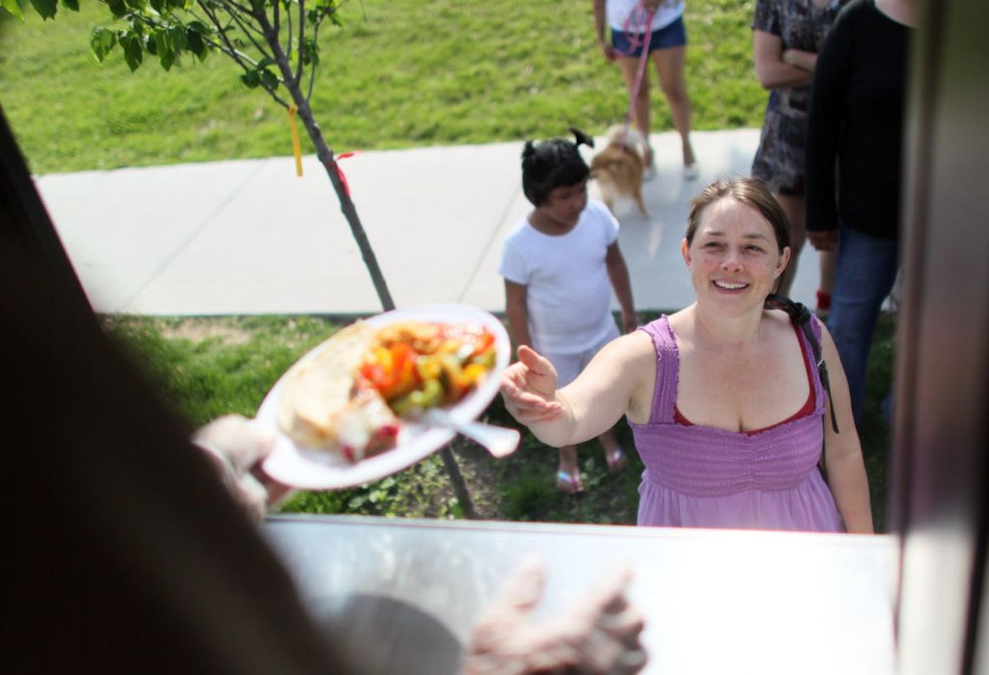 Krista Vrudny of Minneapolis reached for a plate of fajitas as the Sisters' Camelot kitchen bus served meals in Minneapolis near Franklin Avenue and Chicago Avenue Thursday.