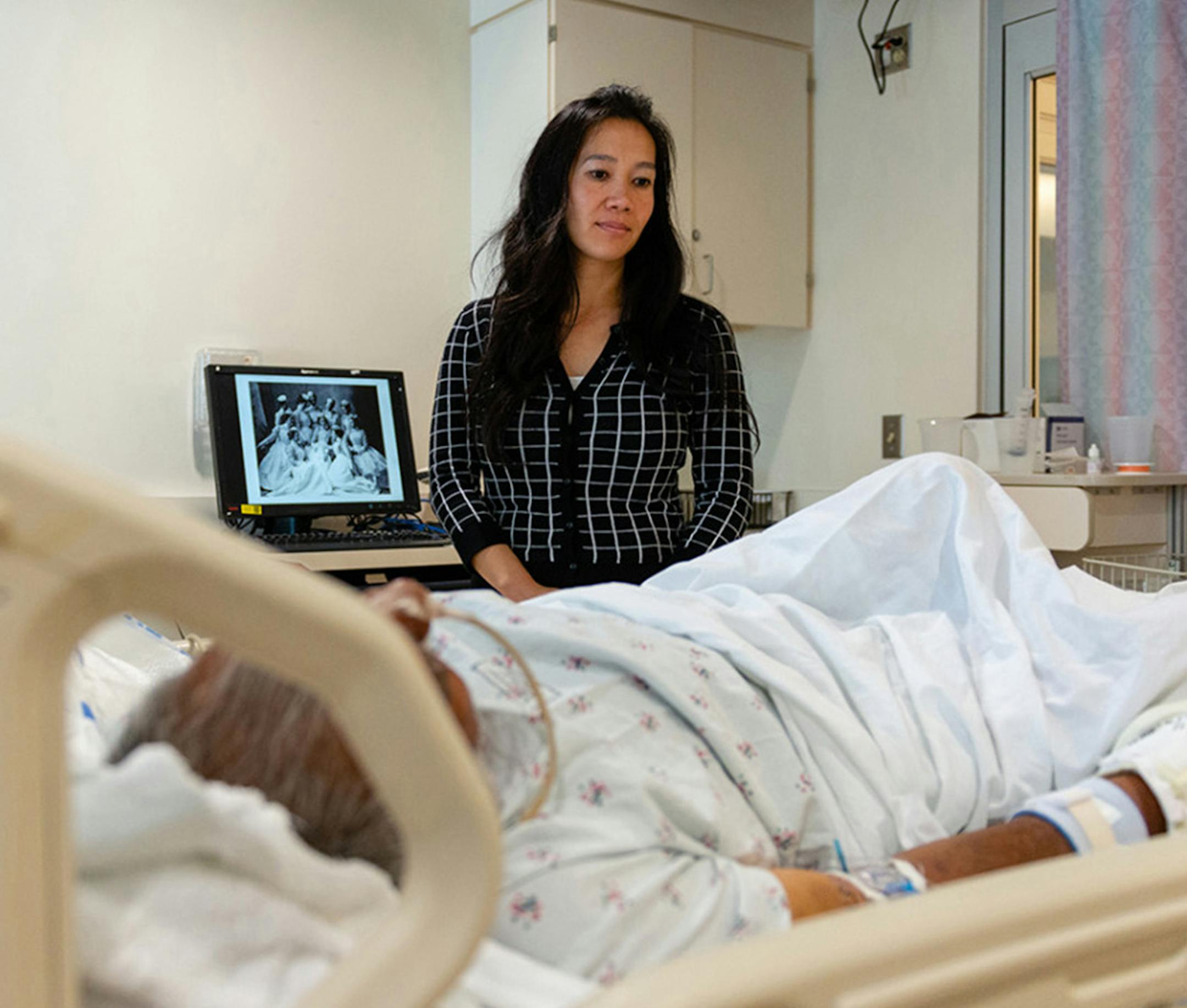 Lenh Vuong, a clinical social worker at Los Angeles County+USC Medical Center, checks on a former John Doe patient who was recently identified. (Heidi de Marco/Kaiser Health News/TNS)