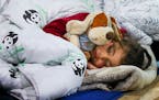 A migrant child sleeps inside a logistics center at the checkpoint “Kuznitsa” at the Belarus-Poland border near Grodno, Belarus, Tuesday, Nov. 23,