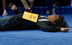Faizan Zaki, 13, of Dallas, lays on the stage after winning the 2025 Scripps National Spelling Bee at the Gaylord National Resort & Convention Center