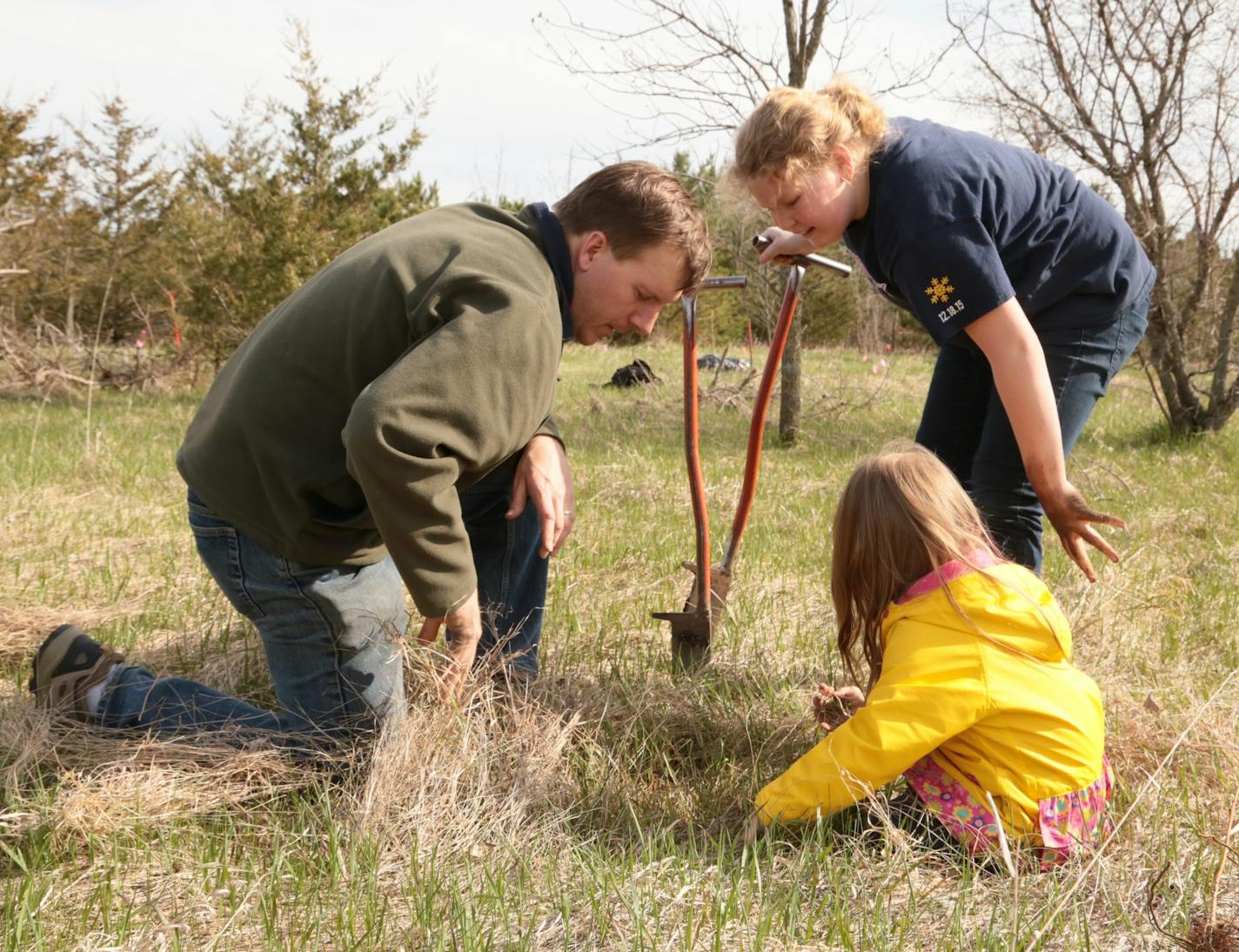 Nick Snavely helps his daughter, Hazel (right), and Anna Sieg plant a tree in the Clearview Elementary School forest on Arbor Day.