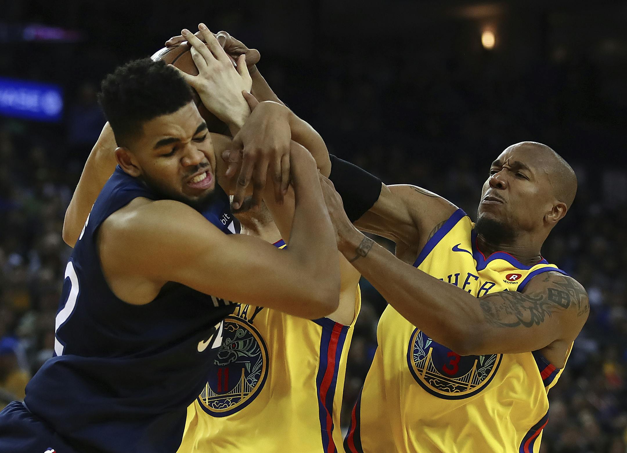 Minnesota Timberwolves' Karl-Anthony Towns, left, fights for the ball with Golden State Warriors' David West, right, and Klay Thompson during the first half of an NBA basketball game Thursday, Jan. 25, 2018, in Oakland, Calif. (AP Photo/Ben Margot)