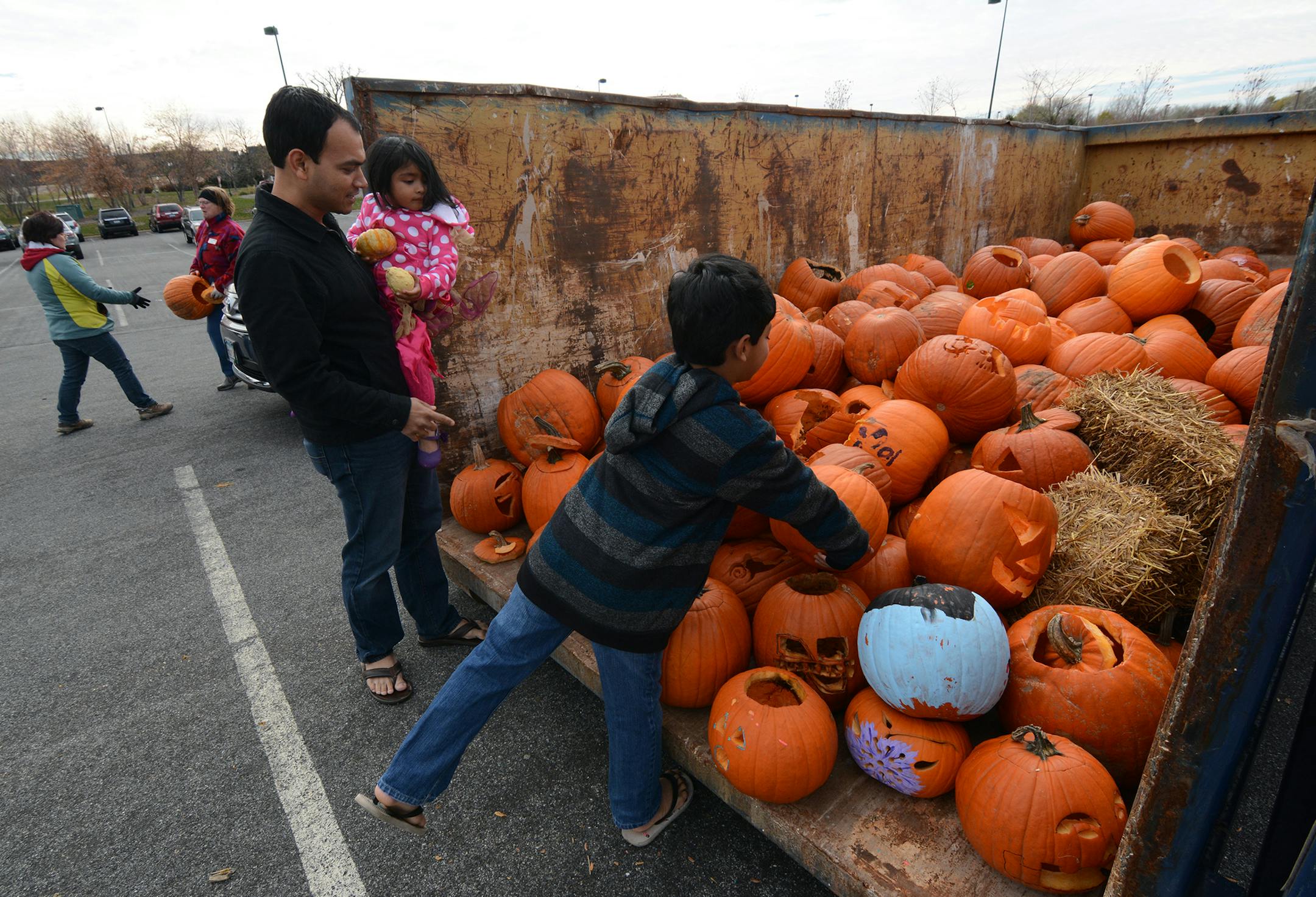 Eagan residents Sam Jena, Shreyan Jena, 7, and Sanah Jena, 2, put pumpkins into the bin at the Eagan Community Center. Master recycler-composter Claudia Zweber, of Eagan, holds a pumpkin in the background. Photo by Liz Rolfsmeier, Special to the Star Tribune