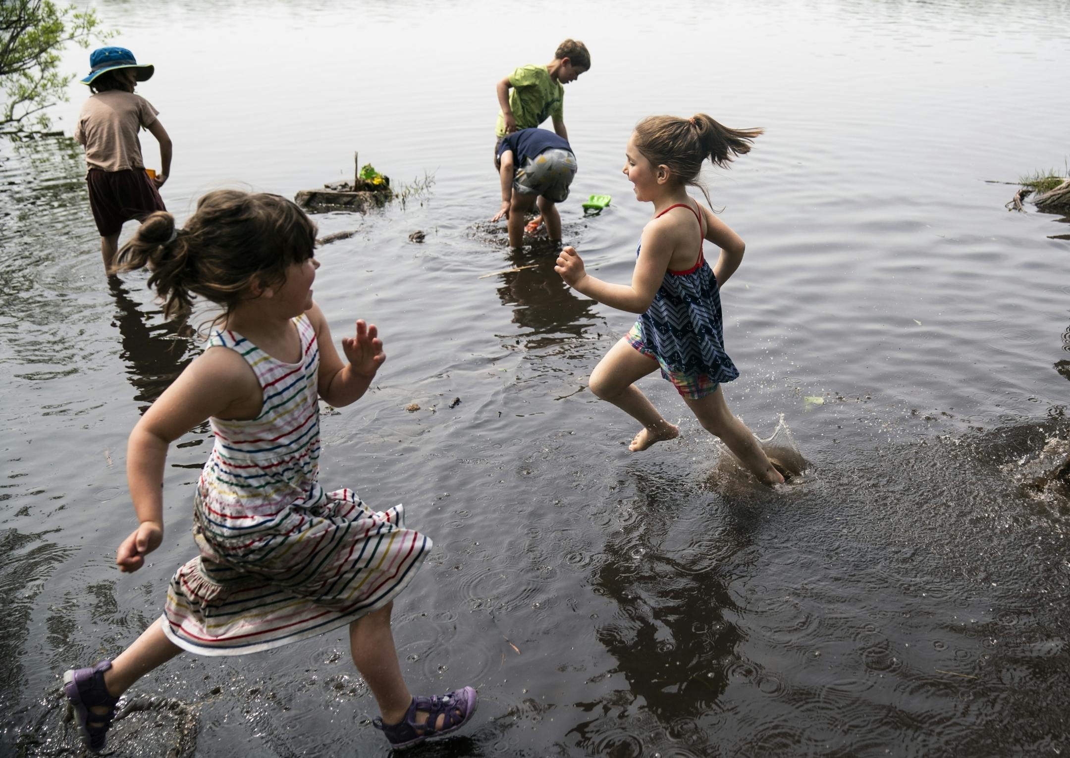 Fern Carmody and Eliana Batista ran past Wylee Olson, Nathan Wissink and Patrick Soto as they played with trucks in the water during a end of the year outing for a City of Lakes Waldorf School kindergarten class on a warm afternoon at Cedar Lake in Minneapolis, Minn., on Thursday, May 30, 2019.