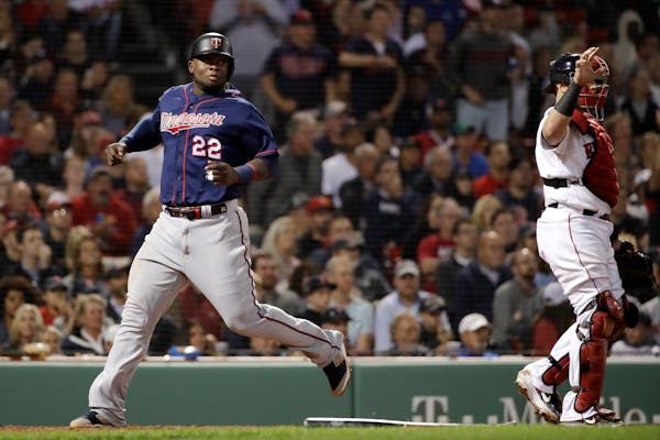 The Twins' Miguel Sano scores on a single by Willians Astudillo as Boston catcher Christian Vazquez stands at right during the seventh inning on Thurs