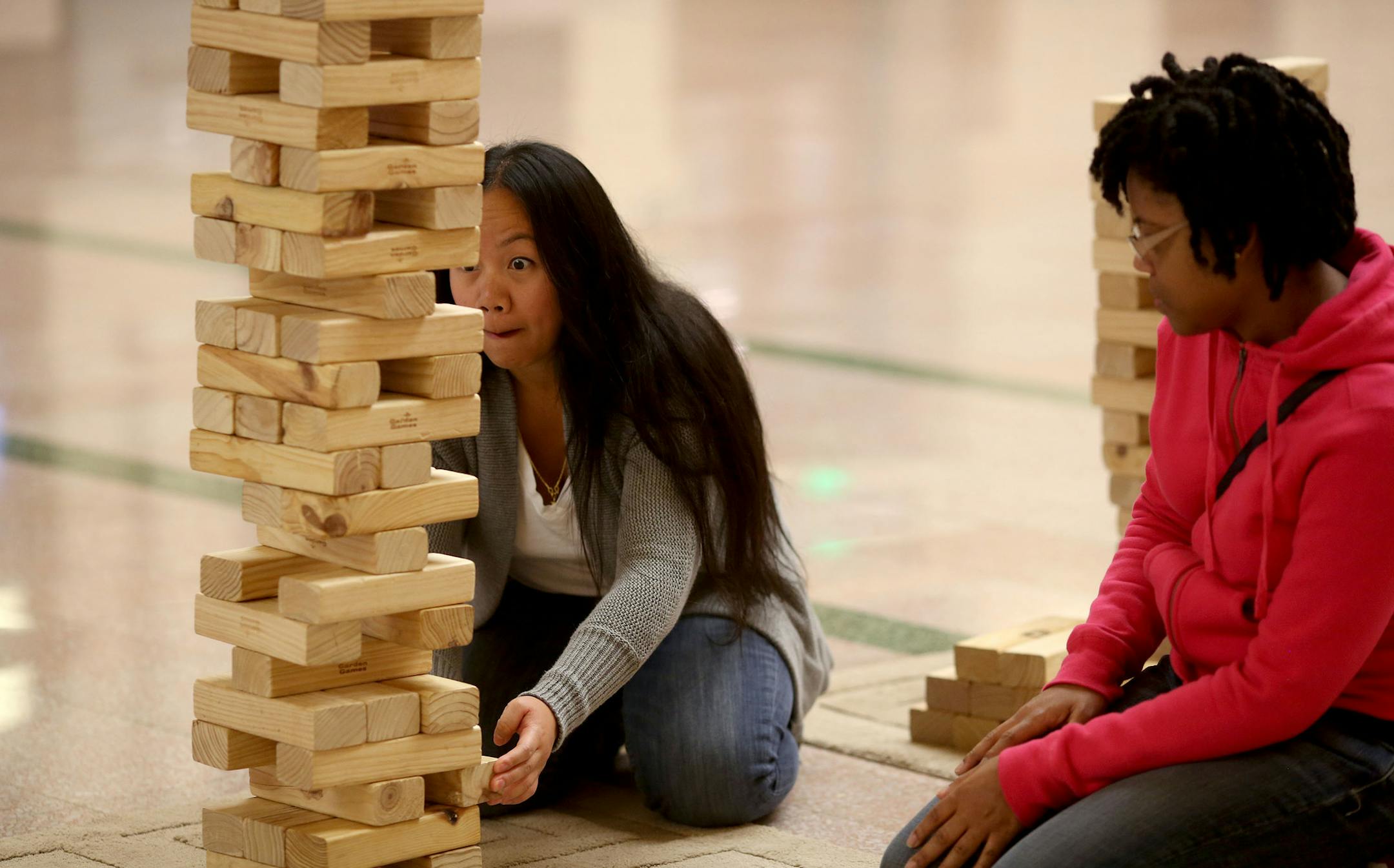 M.K. Xiong, of Minneapolis, carefully removed a piece as she and Yolanda Rogers, of St. Paul, played Jenga ] (KYNDELL HARKNESS/STAR TRIBUNE) kyndell.harkness@startribune.com The Union Depot on game night in St. Paul Min., Wednesday, October 15, 2014.