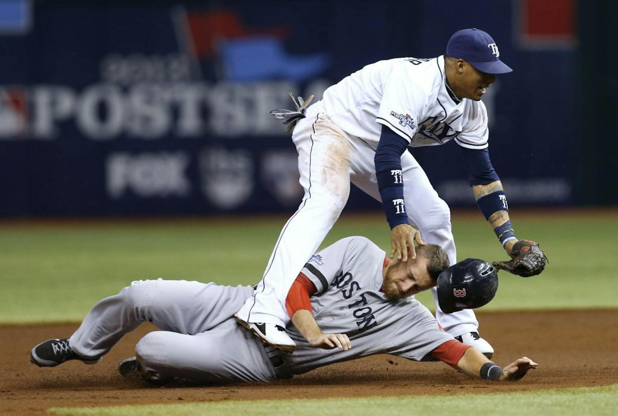 Boston Red Sox's Will Middlebrooks (16) slides under Tampa Bay Rays shortstop Yunel Escobar (11) after he was tagged out on a double play in the third inning in Game 4 of an American League baseball division series, Tuesday, Oct. 8, 2013, in St. Petersburg, Fla.