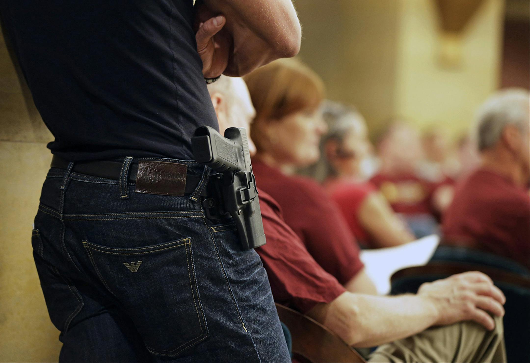 FILE - In this Aug 20, 2013 file photo, a Glock handgun is holstered on the side of Kristopher Kranz of Bloomington, Minn., as he listens to a legislative committee in St. Paul, Minn., during debate on whether Minnesota's rules for carrying a gun in the State Capitol need revising, An advisory committee chaired by Lt. Gov. Yvonne Prettner Solon met Tuesday, Nov. 26, 2013 to consider recommendations to the Legislature for improving Capitol security. (AP Photo/Jim Mone,File) ORG XMIT: MIN201401081