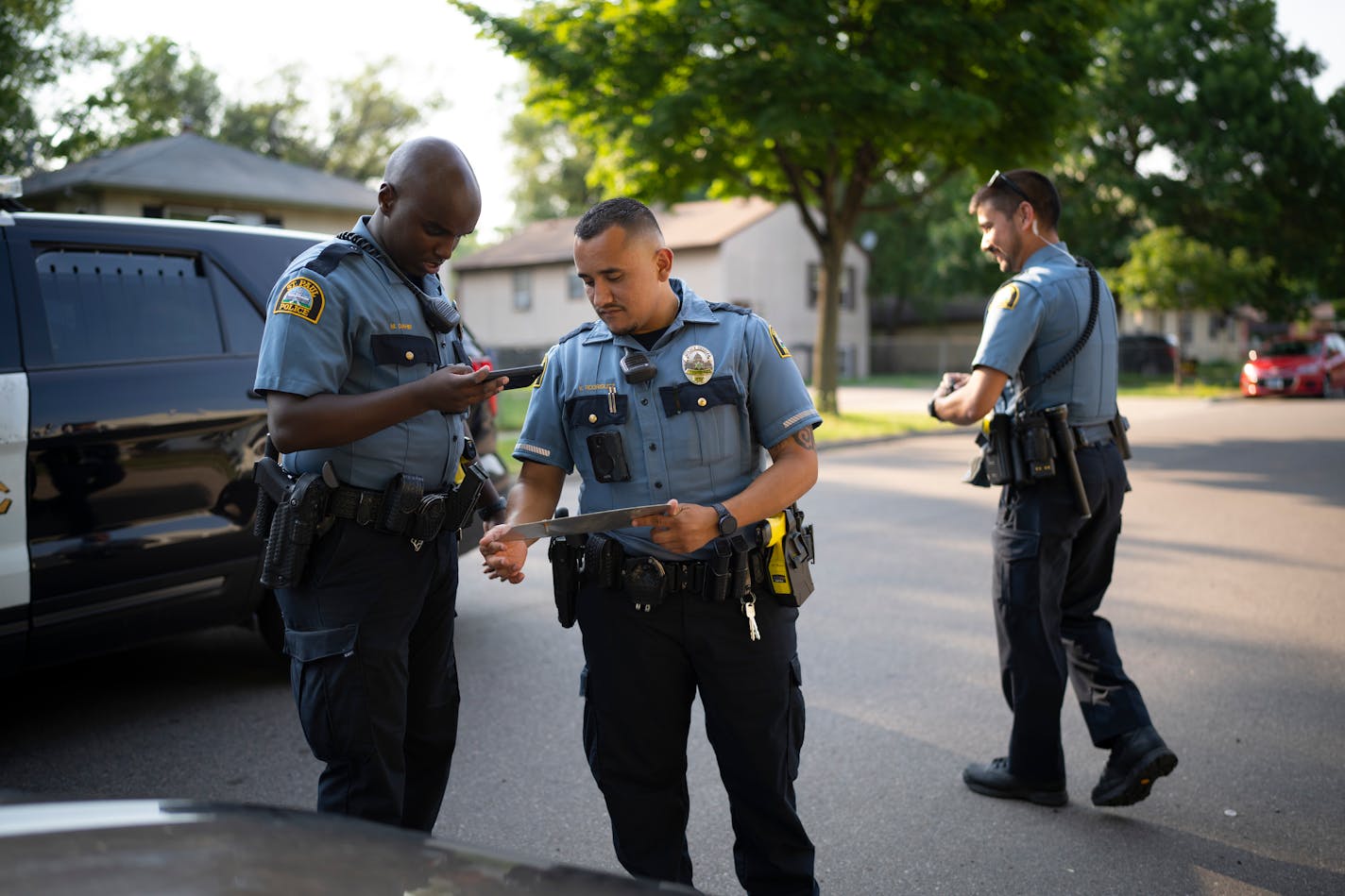 St. Paul Police Officers Mahamed Dahir photographed a license plate reported stolen that his partner, Victor Rodriguez and Officer Rich McGuire, right, removed from the front of a vehicle parked on Norton St. ] JEFF WHEELER • jeff.wheeler@startribune.com