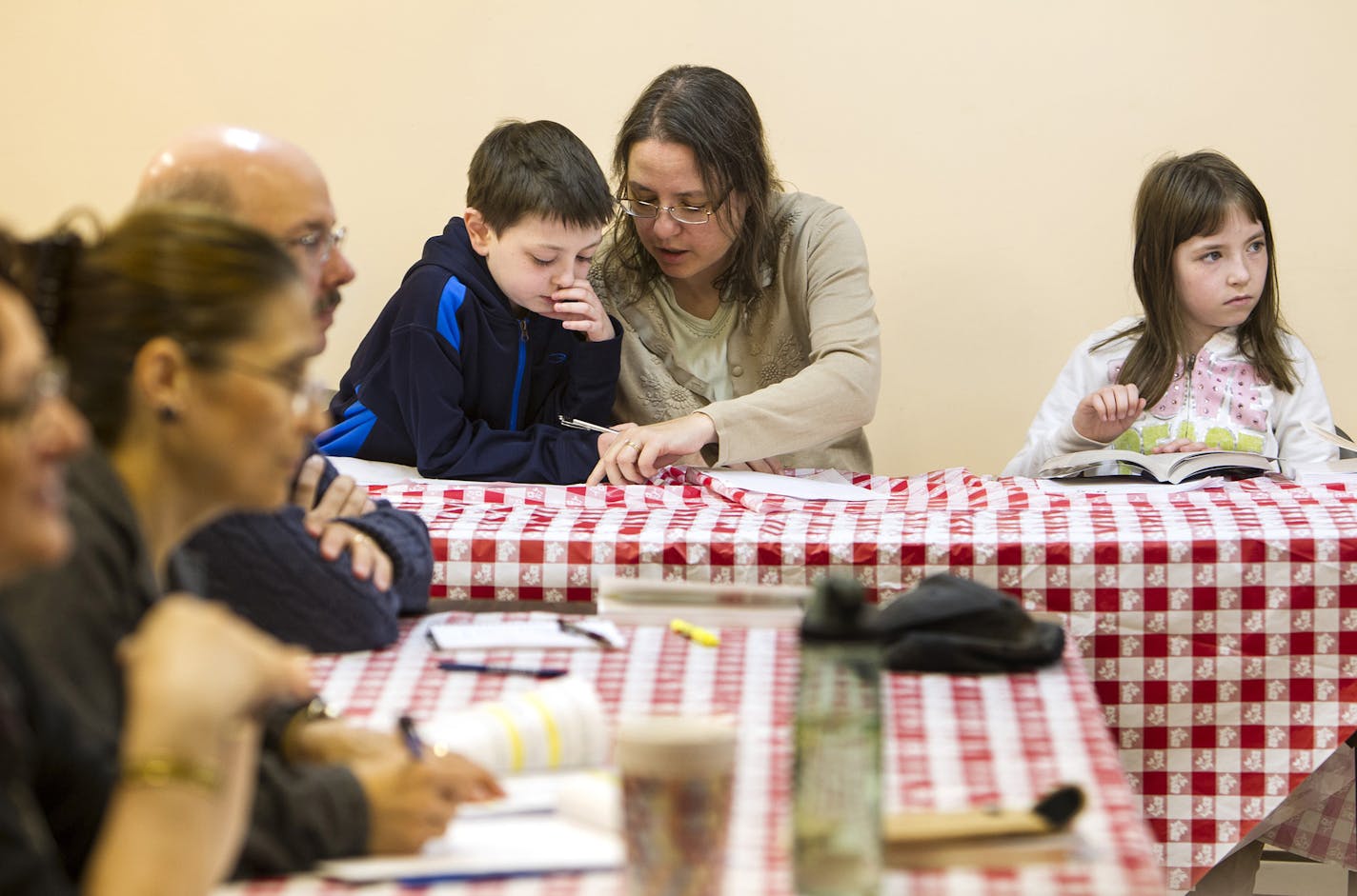 Becky Path, center, helps her son Ben, 11, with a translation as her daughter April, 9, looks to the teacher during Romanian language class at Saint Stephen Romanian Orthodox Church in South Saint Paul September 14, 2013. Becky is half Romanian, and her father, brother, and sister are also taking the class. (Courtney Perry/Special to the Star Tribune)