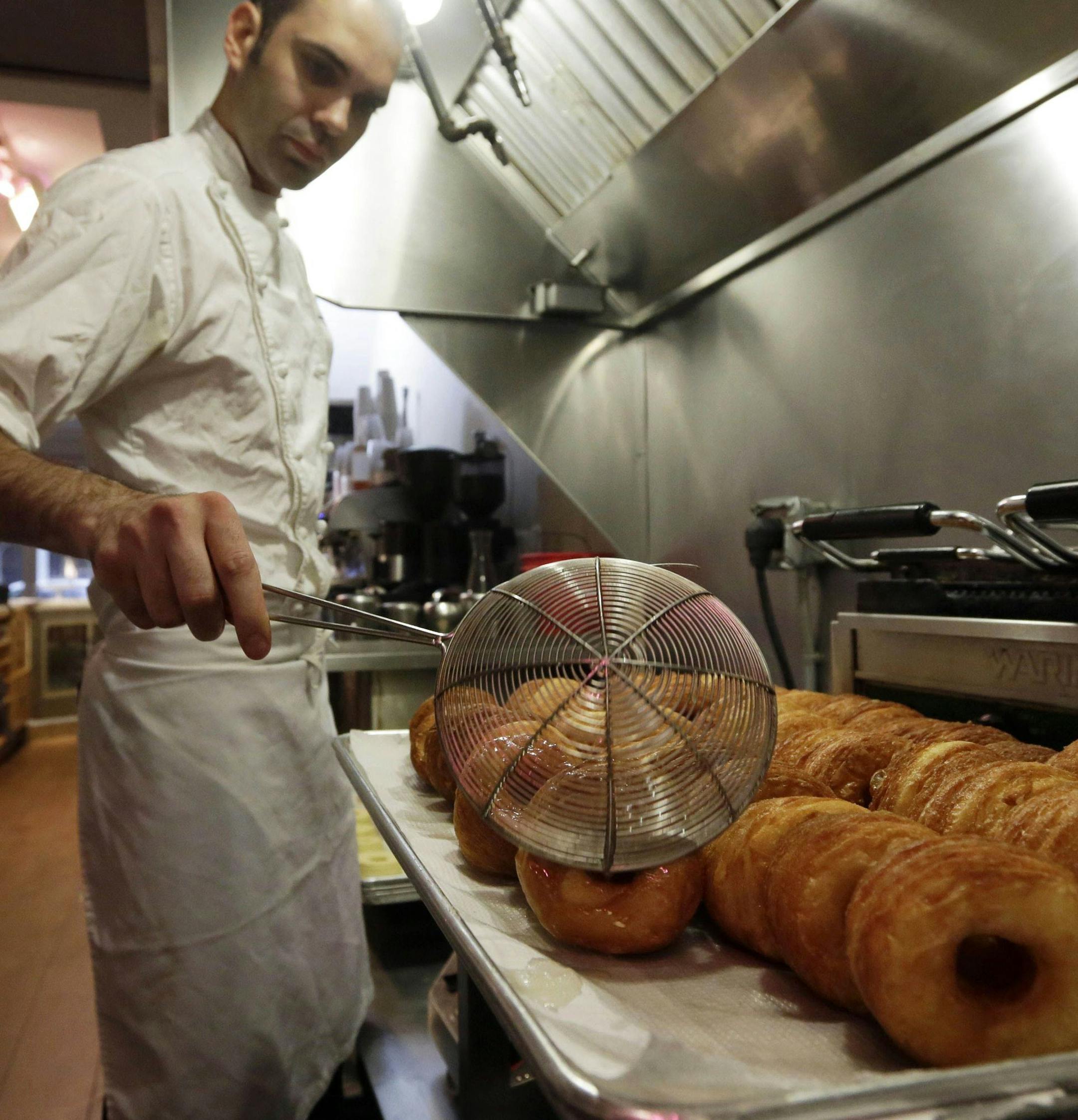 FILE - In this June 3, 2013 file photo, chef Dominique Ansel makes Cronuts, a croissant-donut hybrid, at the Dominique Ansel Bakery in New York. The mashup of a croissant and doughnut was written up and photographed by food blog Grub Street. It quickly spread online and beyond. "By the end of the first week, we had over 100 people in line," says Ansel. (AP Photo/Richard Drew, File) ORG XMIT: NYBZ202