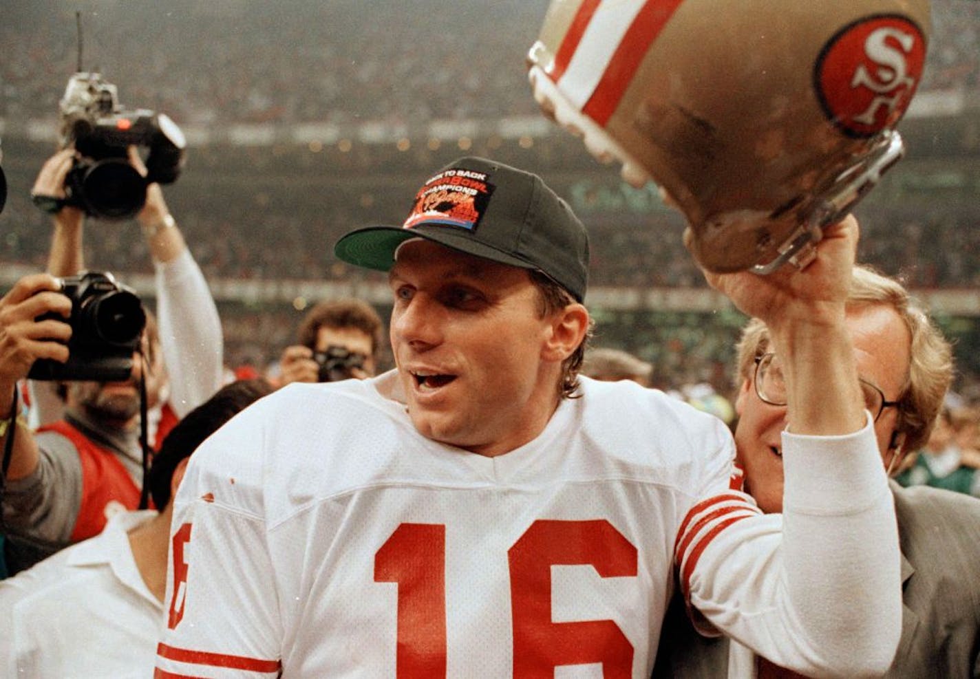 San Francisco 49ers quarterback Joe Montana raises his helmet toward the crowd as he leaves the field following the team's 55-10 victory over the Denver Broncos in the Super Bowl in New Orleans, La., Jan. 28, 1990.