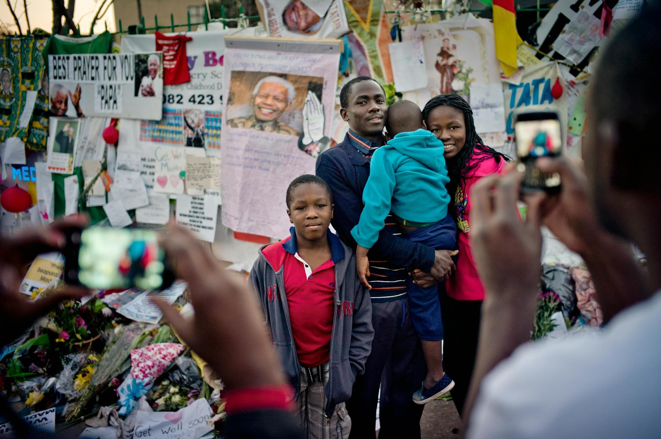 People have their pictures taken next to a makeshift shrine for Nelson Mandela, the iconic South African leader, in Pretoria, South Africa, where he his hospitalized, on July 4, 2013. Mandela is in critical condition with a lung infection. (Tomas Munita/The New York Times)