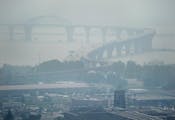 As the Greenwood Fire continues to burn, smoke from the blaze fills the air, almost obscuring the Bong Bridge and Denfeld Senior High School, bottom t