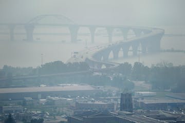 As the Greenwood Fire continues to burn, smoke from the blaze fills the air, almost obscuring the Bong Bridge and Denfeld Senior High School, bottom t