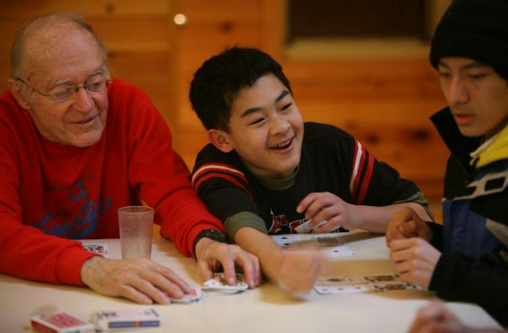 Dave Moore, the troop's scoutmaster for 29 years, played golf (the card game) with a laughing David Her, 13, and other scouts at Camp Ajawah.