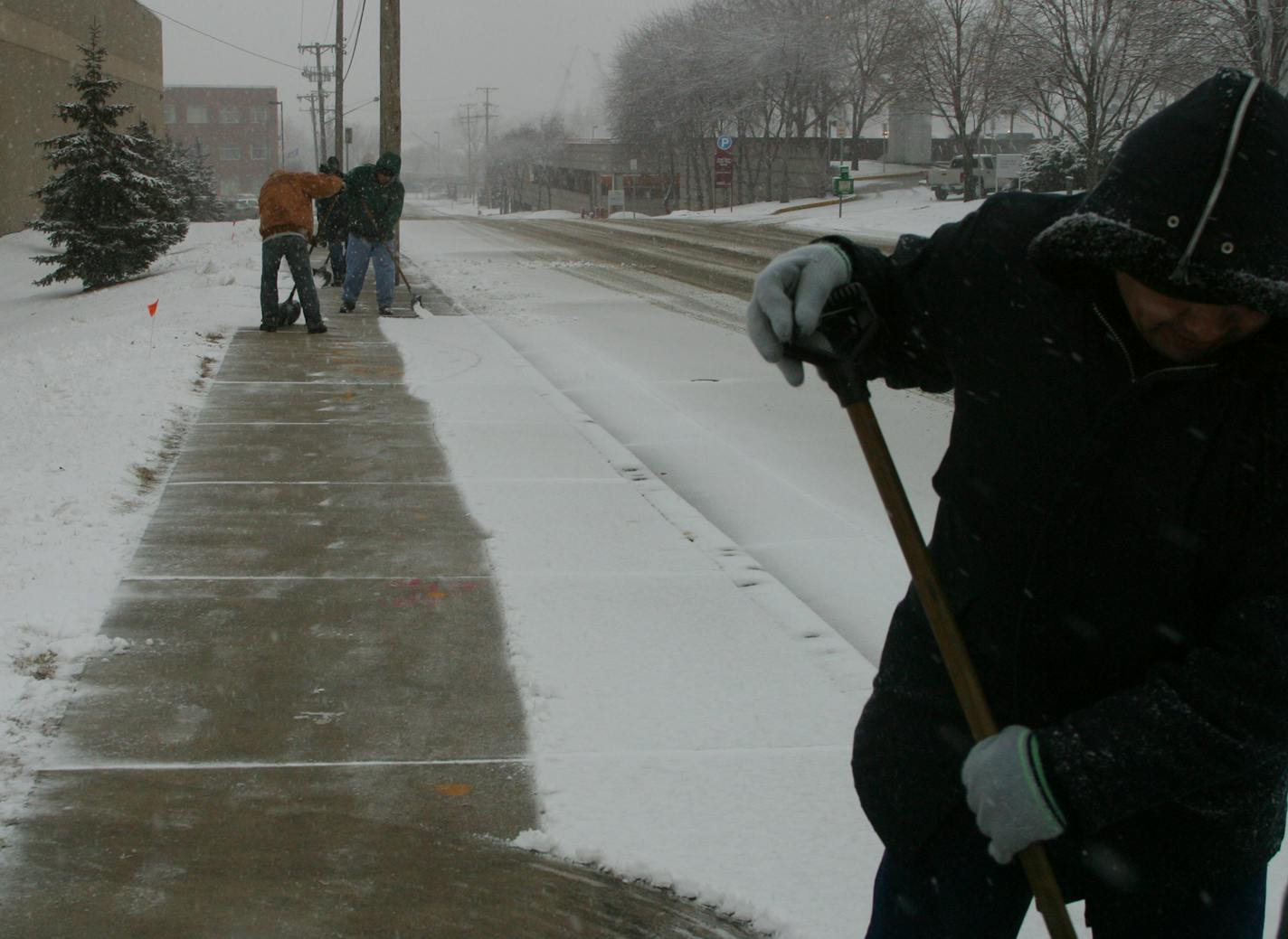 A crew of shovelers clears the sidewalk of Cenveo, 208 11th Av. S., in Minneapolis early Friday. A spring snowstorm was expected to dump several inches of snow across the Twin Cities metro.