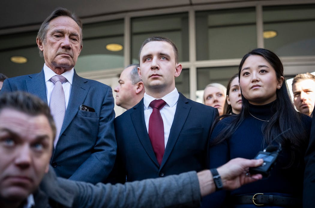 Trooper Ryan Londregan, center in maroon tie, stood hand-in-hand with his wife, Grace Londregan, surrounded by security, defense attorney Peter Wold, left, his lawyers and dozens of supporters, including many officers, as his lawyer spoke to the media after his first court appearance.