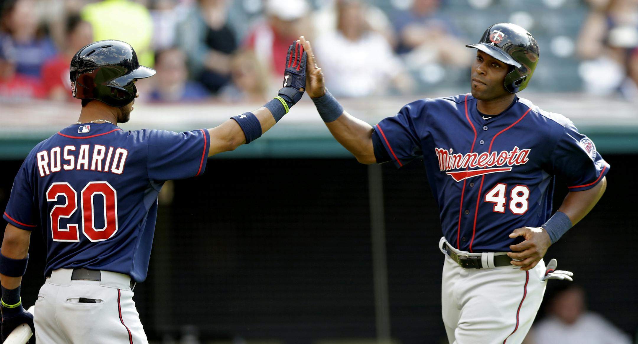 Minnesota Twins' Torii Hunter (48) is congratulated by Eddie Rosario (20) after Hunter scored on an RBI-single from Eduardo Escobar in the third inning of a baseball game against the Cleveland Indians, Saturday, May 9, 2015, in Cleveland. (AP Photo/Tony Dejak)