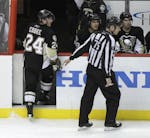 In this photo from March 20, 2011, Pittsburgh Penguins' Matt Cooke (24) is escorted from the ice by NHL linesman Derek Amell (75) after he was ejected