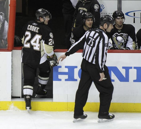In this photo from March 20, 2011, Pittsburgh Penguins' Matt Cooke (24) is escorted from the ice by NHL linesman Derek Amell (75) after he was ejected