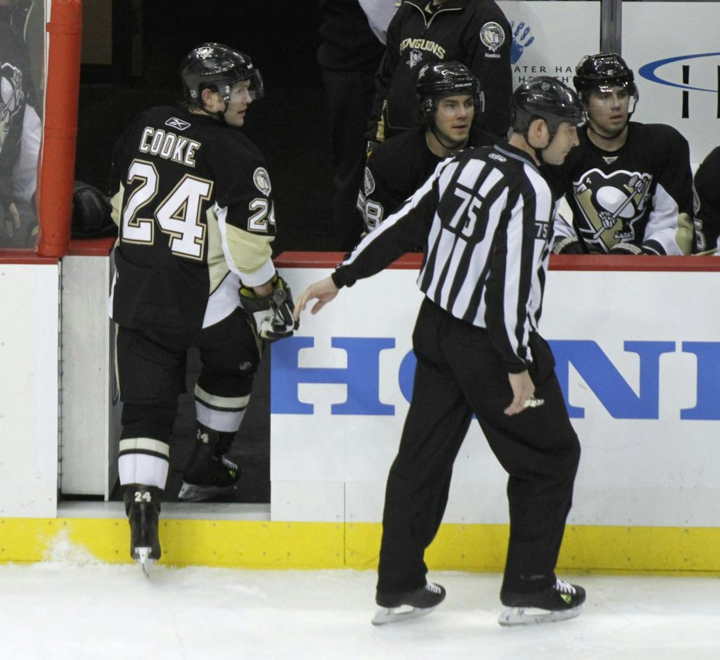 In this photo from March 20, 2011, Pittsburgh Penguins' Matt Cooke (24) is escorted from the ice by NHL linesman Derek Amell (75) after he was ejected for elbowing New York Rangers defenseman Ryan McDonagh