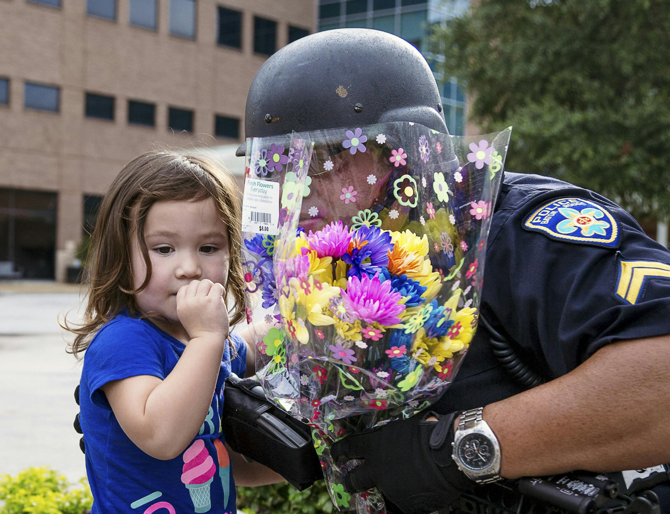 Suzannah Clark gives flowers to police guarding Our Lady of the Lake Regional Medical Center, where officers who were injured in a shooting were taken, in Baton Rouge, La., July 17, 2016. Three law enforcement officers were fatally shot and at least three others wounded Sunday, the East Baton Rouge Parish SheriffÌs Office said. The gunman, who was identified as Gavin Long of Kansas City, Mo., was killed by the police. (Bryan Tarnowski/The New York Times) ORG XMIT: MIN2016071719275686