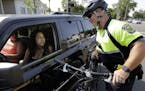 In this July 20, 2016 photo, police officer Matthew Monteiro speaks to a motorist about texting while driving while patrolling on his bicycle in East 