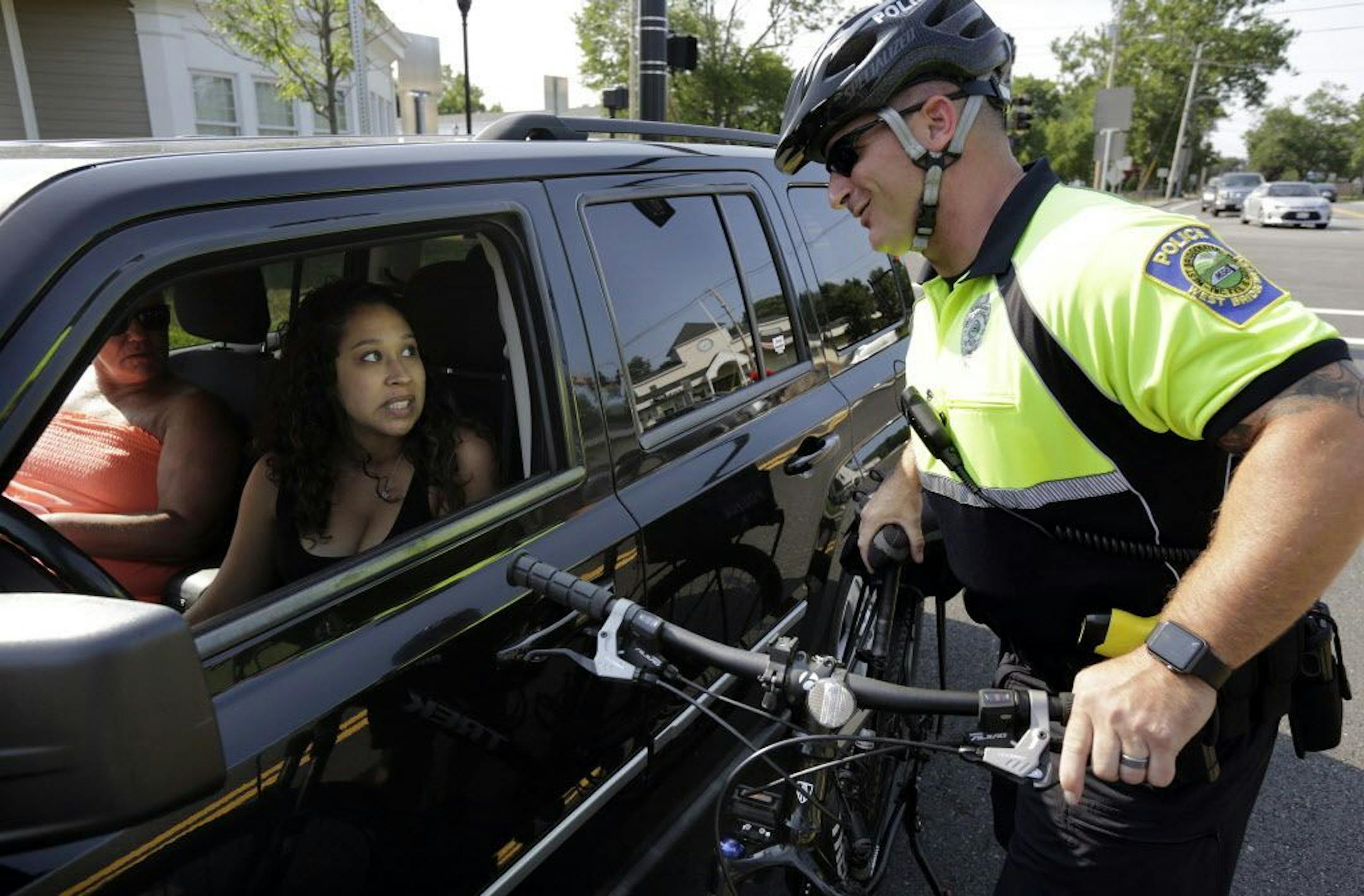 In this July 20, 2016 photo, police officer Matthew Monteiro speaks to a motorist about texting while driving while patrolling on his bicycle in East Bridgewater, Mass. Efforts to discourage drivers from texting have increased in recent years, but the consensus is that the problem is only getting worse. Police departments around the country have gotten creative in trying to get drivers to put down their phones.