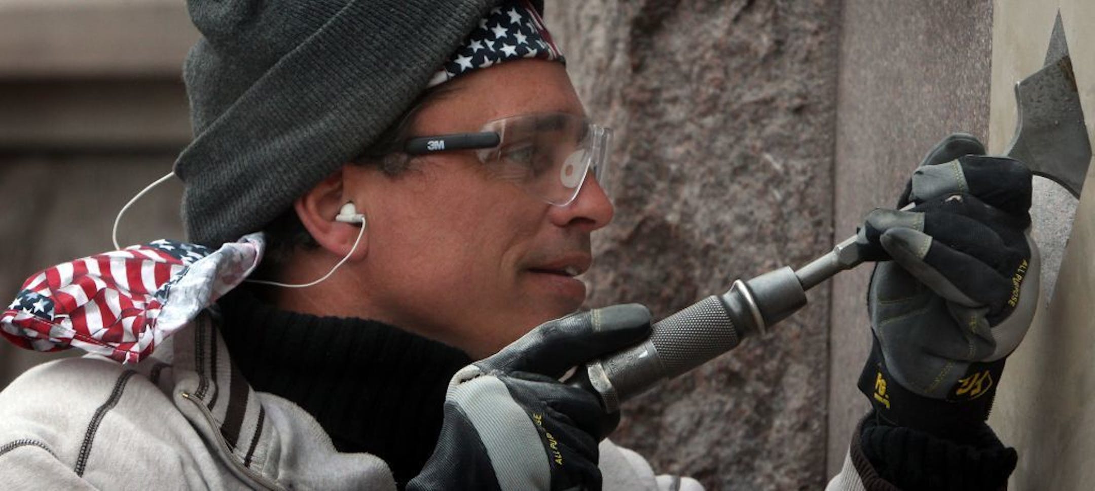 Using gloves to keep his hands warm in the unusually cold, April weather, stone carver Andy DelGallo, owner of Eastern Memorials (located in Manassas, VA), used a pneumatic chisel and other tools to cut and shape letters in the Minneapolis City Hall-Cour