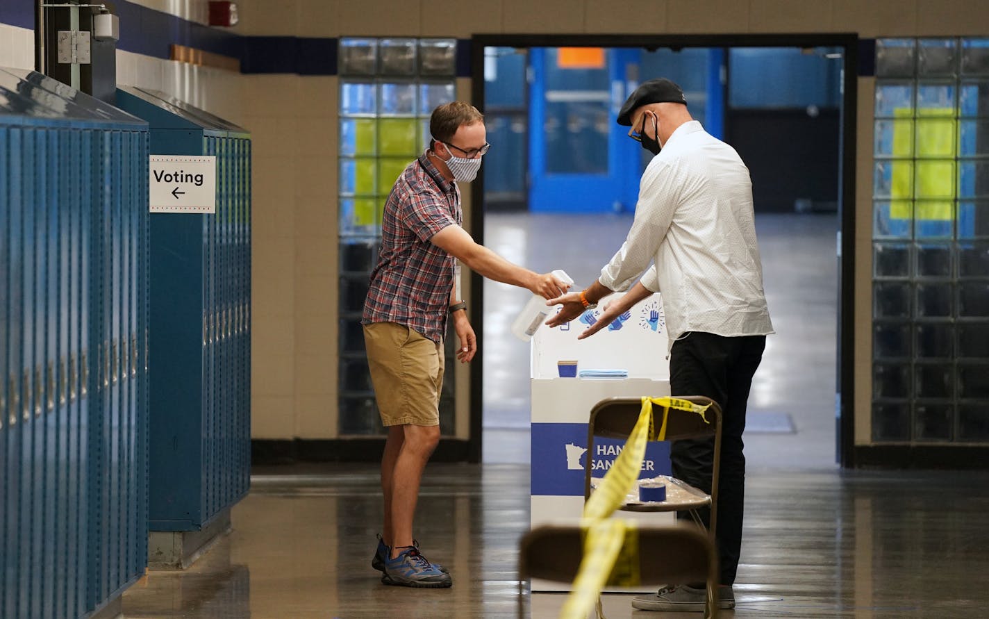 Election judge Tyler Sahnow gave a spray of hand sanitizer to John Enloe as he arrived to vote Tuesday morning at Northeast Middle School in Minneapolis. ] ANTHONY SOUFFLE • anthony.souffle@startribune.com Citizens cast their primary ballots during the first election in Minnesota since the full outbreak of the COVID-19 pandemic Tuesday, Aug. 11, 2020 in Minneapolis.