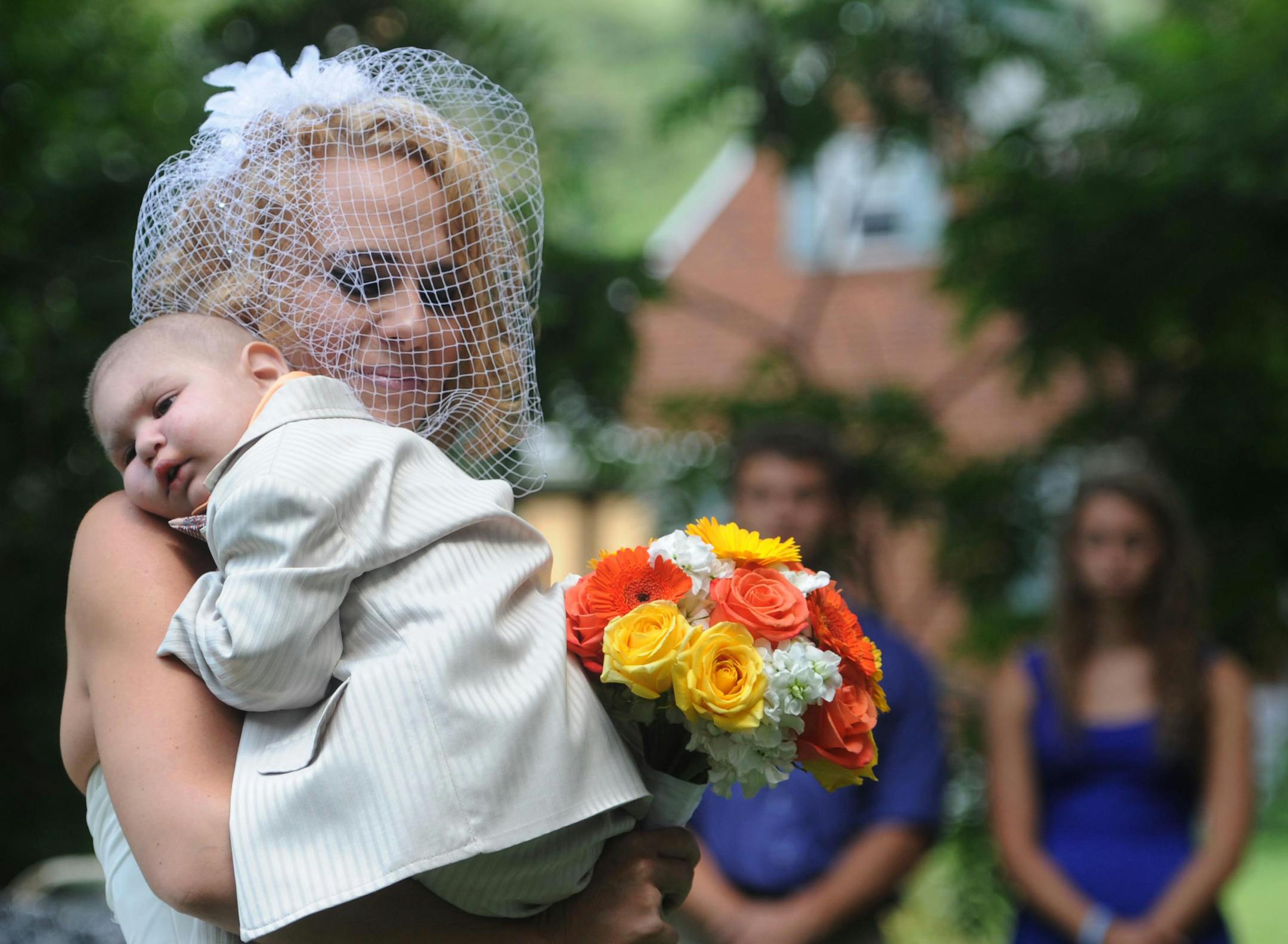 Christine Swidorsky carries her son and the couple's best man, Logan Stevenson, 2, down the aisle to her husband-to-be Sean Stevenson during the wedding ceremony on Saturday, Aug. 3, 2013 in Jeannette, Pa. The Stevensons abandoned an original wedding date of July 2014 after learning from doctors late last month that their son had two to three weeks to live.