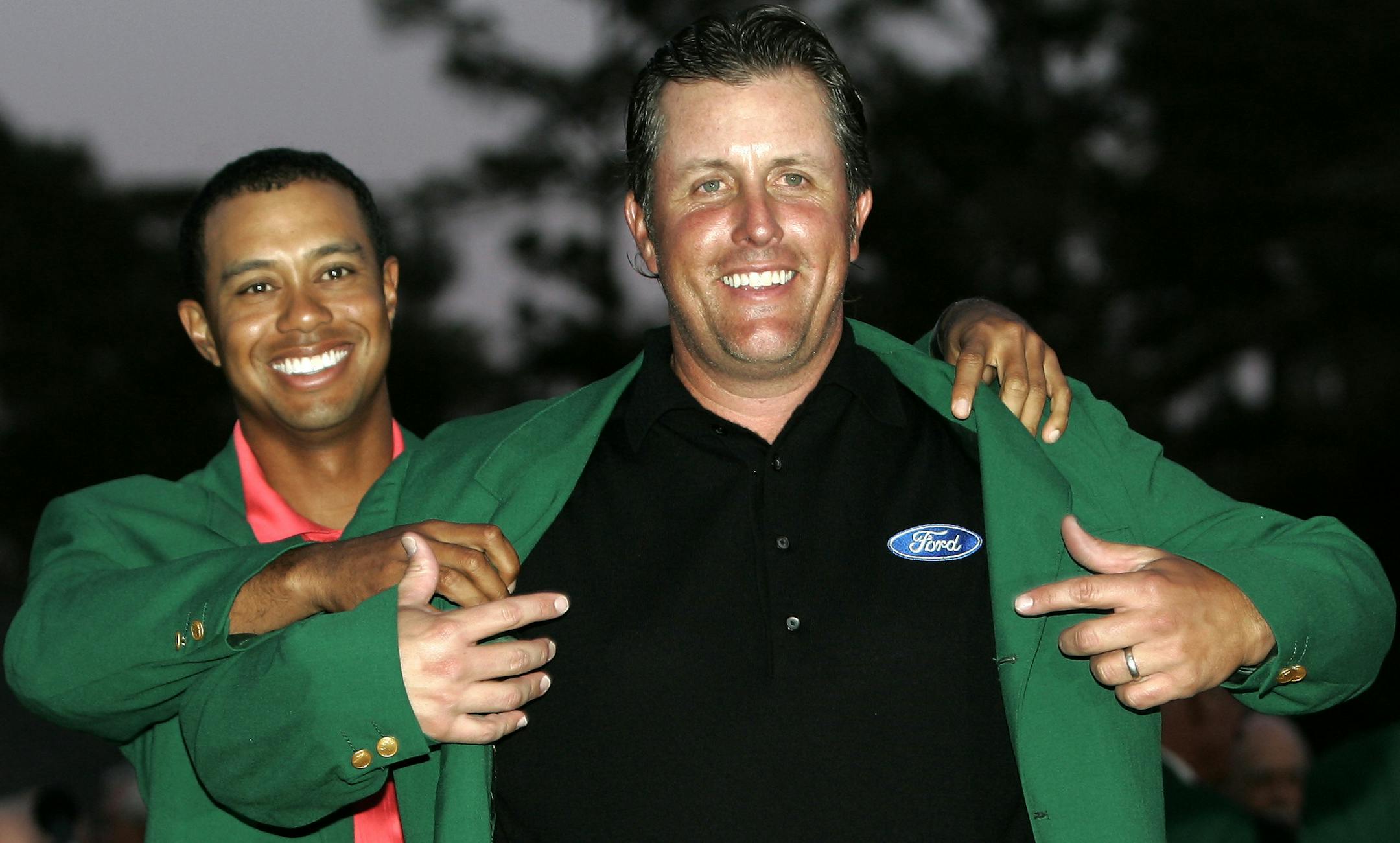 Phil Mickelson, right, gets his Masters Green Jacket from last years champion Tiger Woods after winning the 2006 Masters golf tournament at the Augusta National Golf Club in Augusta, Ga., Sunday, April 9, 2006. (AP Photo/Amy Sancetta) ORG XMIT: AUH288