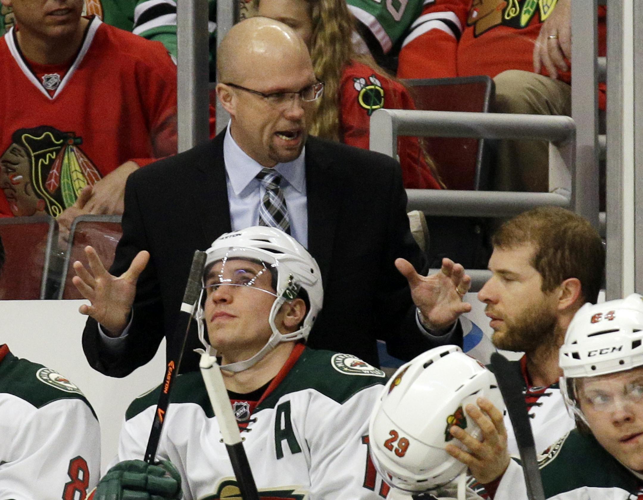 Minnesota Wild head coach Mike Yeo, top, talks to his team during the first period in Game 1 of an NHL hockey second-round playoff series against the Chicago Blackhawks in Chicago, Friday, May 2, 2014. (AP Photo/Nam Y. Huh)