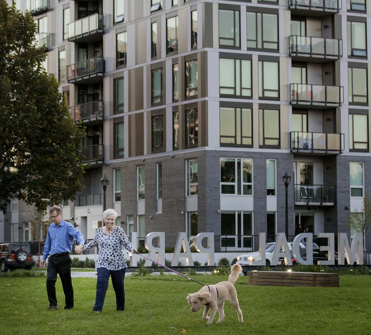 Sam and Kim Thompson walked Abby, their golden doodle, at Gold Medal Park near their condo in the Bridgewater. "We do more, walk more, eat out more," said Sam of downtown living. "Every day's a vacation."