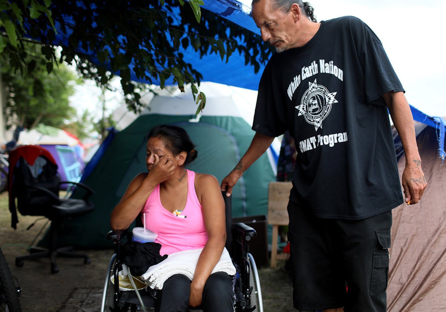 James Cross, the founder of the street outreach group Natives Against Heroin, comforts a woman in her wheelchair who was living at the homeless camp along Hiawatha Avenue in south Minneapolis.