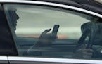 A man uses his cellphone while driving in downtown Minneapolis on Wednesday, a common sight.