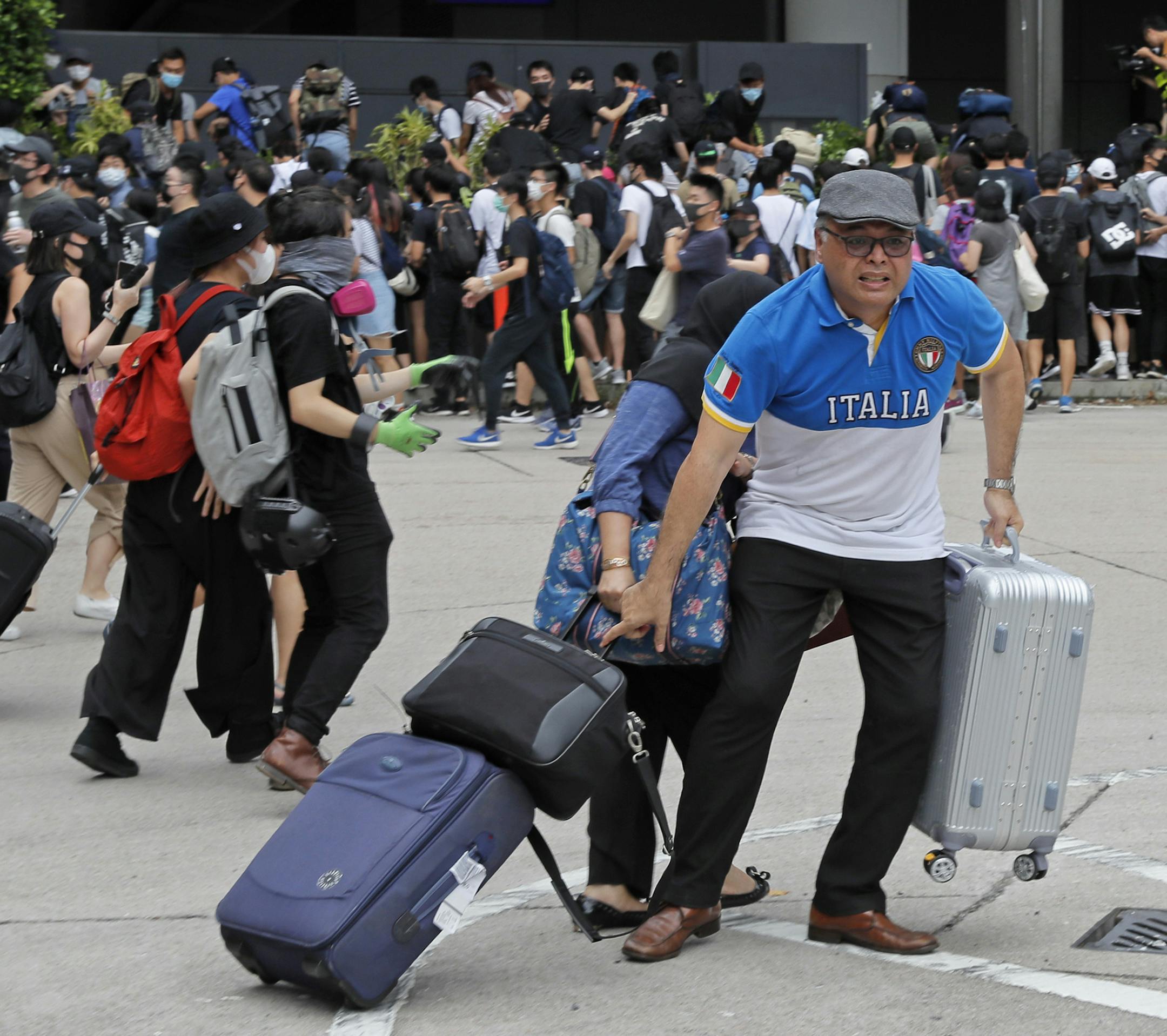 FILE - In this Sept. 1, 2019, file photo, passengers and pro-democracy protestors run as riot police arrive outside the airport in Hong Kong. Visitor numbers to Hong Kong fell by nearly 40% in the second half of last year amid clashes between police and anti-government protesters. (AP Photo/Kin Cheung, File)