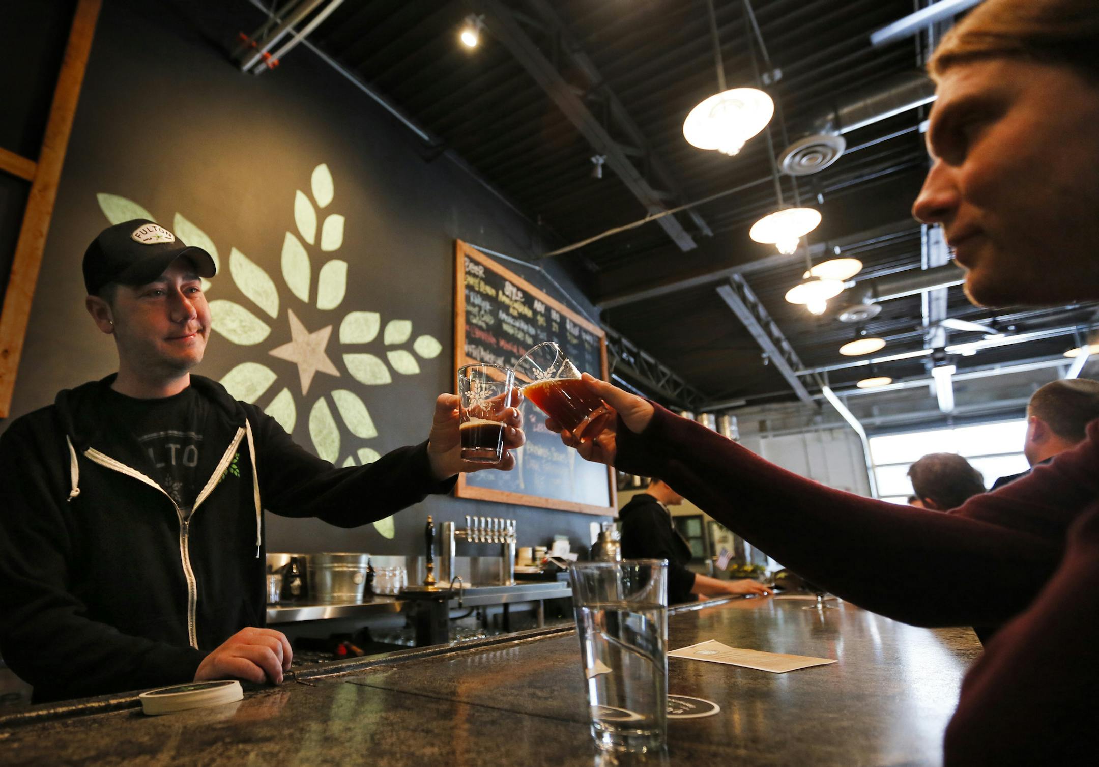 The tap room at Fulton Brewery in Minneapolis was bustling Wednesday afternoon, while lawmakers at the capitol were working on a bill that could allow them to sell their brew on Sunday. Here, Tap Room Manager Justin Janicki (left) served up a brew to Dan Mays (right).