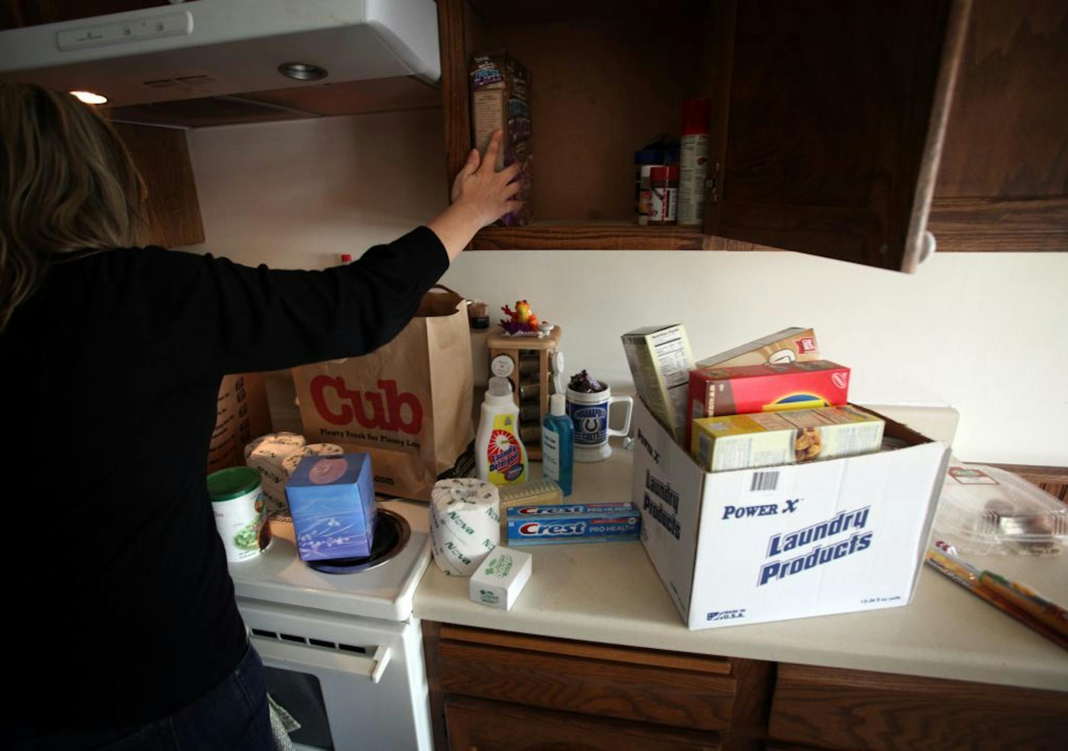Stephanie of Cottage Grove, Minn. filled an empty cubboard at her home with food she got at the Friends in Need Food Shelf in St. Paul Park Tuesday, on September 13, 2011. Stephanie fell behind in her finances after a flood in her basement and a decrease in her hours at work so she went to the food shelf for the first time in a year. "I used to give to the food shelf, knowing one day I may need it," said Stephanie, who is a single mother of two kids.