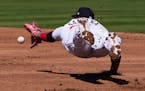 Minnesota Twins first baseman Carlos Santana dives for a line drive single by Pittsburgh Pirates Jake Lamb in the second inning of a spring training b