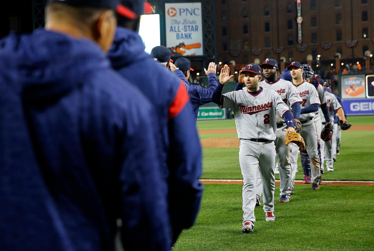 Minnesota Twins second baseman Brian Dozier (2) high-fives teammates as he walks off the field after a baseball game against the Baltimore Orioles, Saturday, March 31, 2018, in Baltimore. Minnesota won 6-2. (AP Photo/Patrick Semansky)