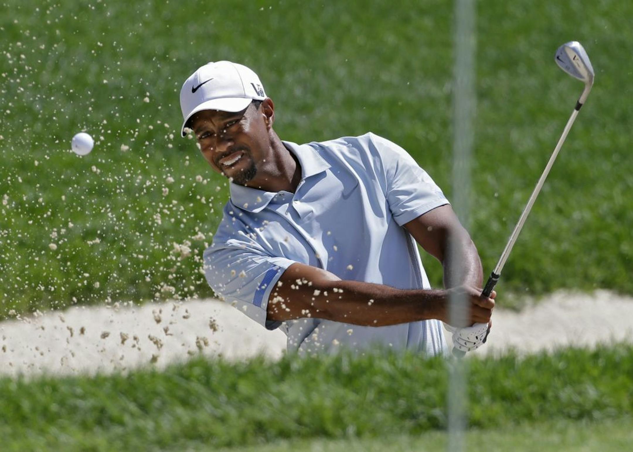 Tiger Woods hits from the sand to the seventh green during the third round of the Bridgestone Invitational golf tournament Saturday, Aug. 3, 2013 at Firestone Country Club in Akron, Ohio.