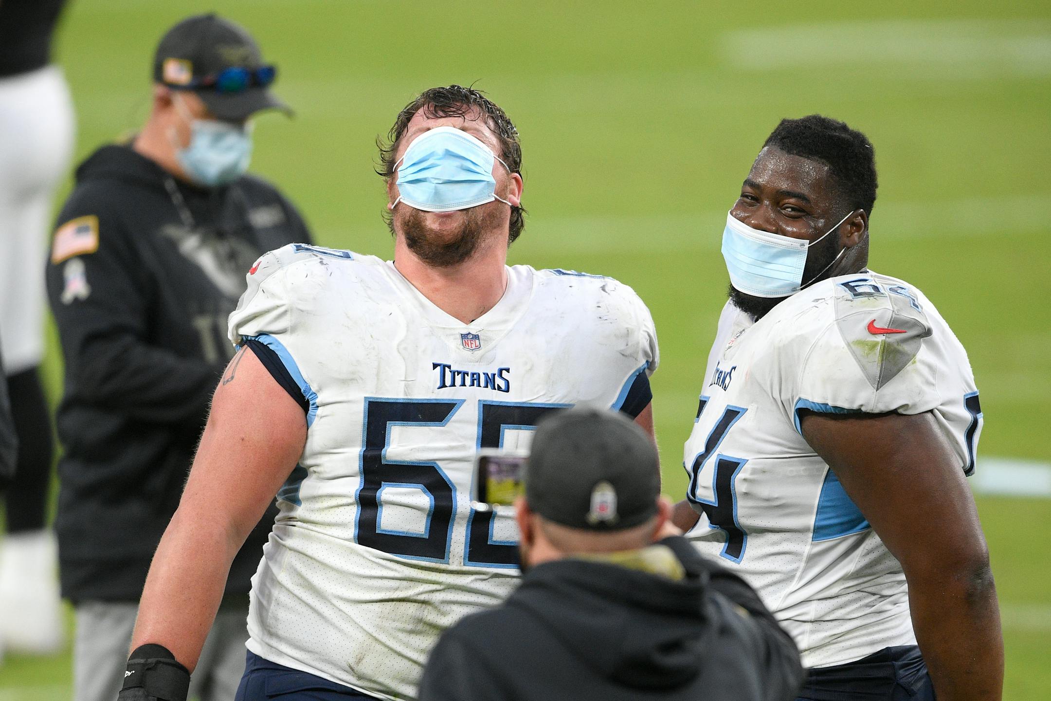 Titans offensive linemen Aaron Brewer, left, and Nate Davis wore face masks while running off the field Sunday. The NFL has announced it will crack down on teams not enforcing the wearing of masks to curb the spread of COVID-19.