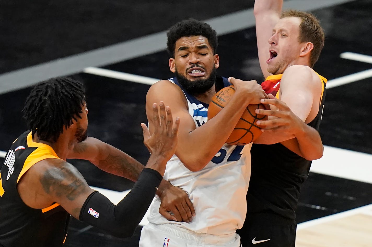 Minnesota Timberwolves center Karl-Anthony Towns, center, grabs a rebound as Utah Jazz's Derrick Favors, left, and Joe Ingles defend during the second half of an NBA basketball game Saturday, Dec. 26, 2020, in Salt Lake City. (AP Photo/Rick Bowmer)