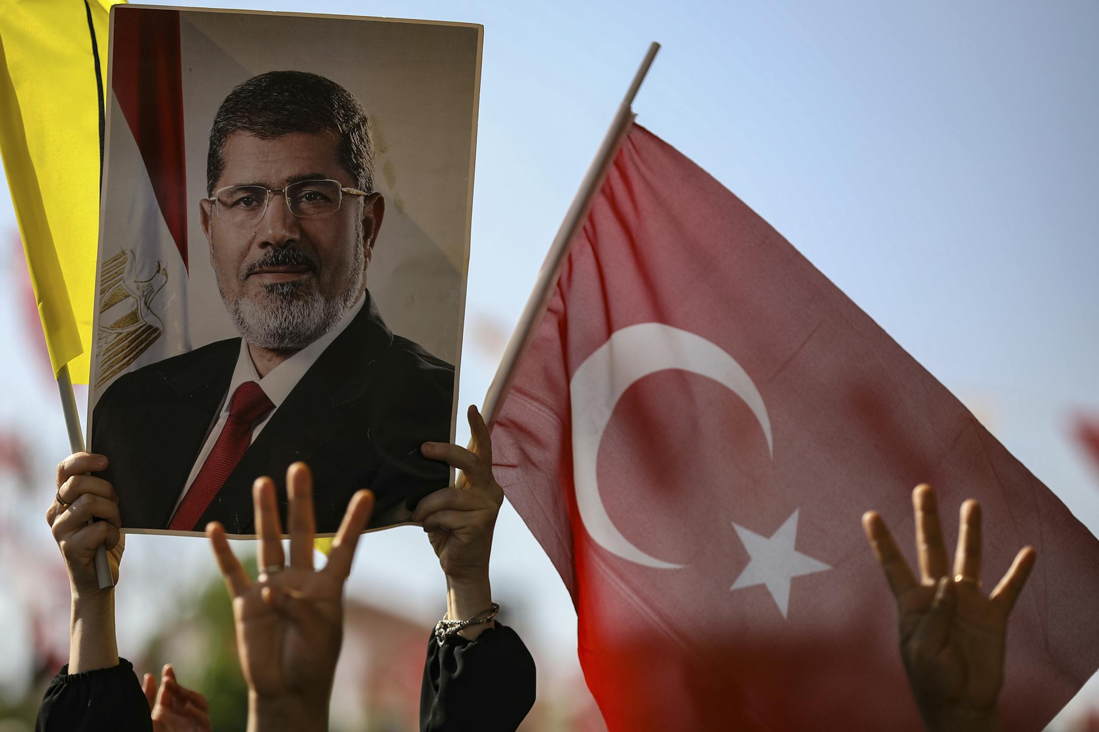 Supporters join Turkish President Recep Tayyip Erdogan, who attends funeral prayers in absentia for ousted former Egyptian President Mohammed Morsi, in poster, at Fatih Mosque in Istanbul, Tuesday, June 18, 2019. Funeral prayers were held in mosques across Turkey for Morsi, who had close ties to Erdogan. The former president, who was ousted by current President Abdel-Fattah el-Sissi in a military coup in 2013, collapsed in a courtroom in Egypt during trial on Monday and died. (AP Photo/Emrah Gur