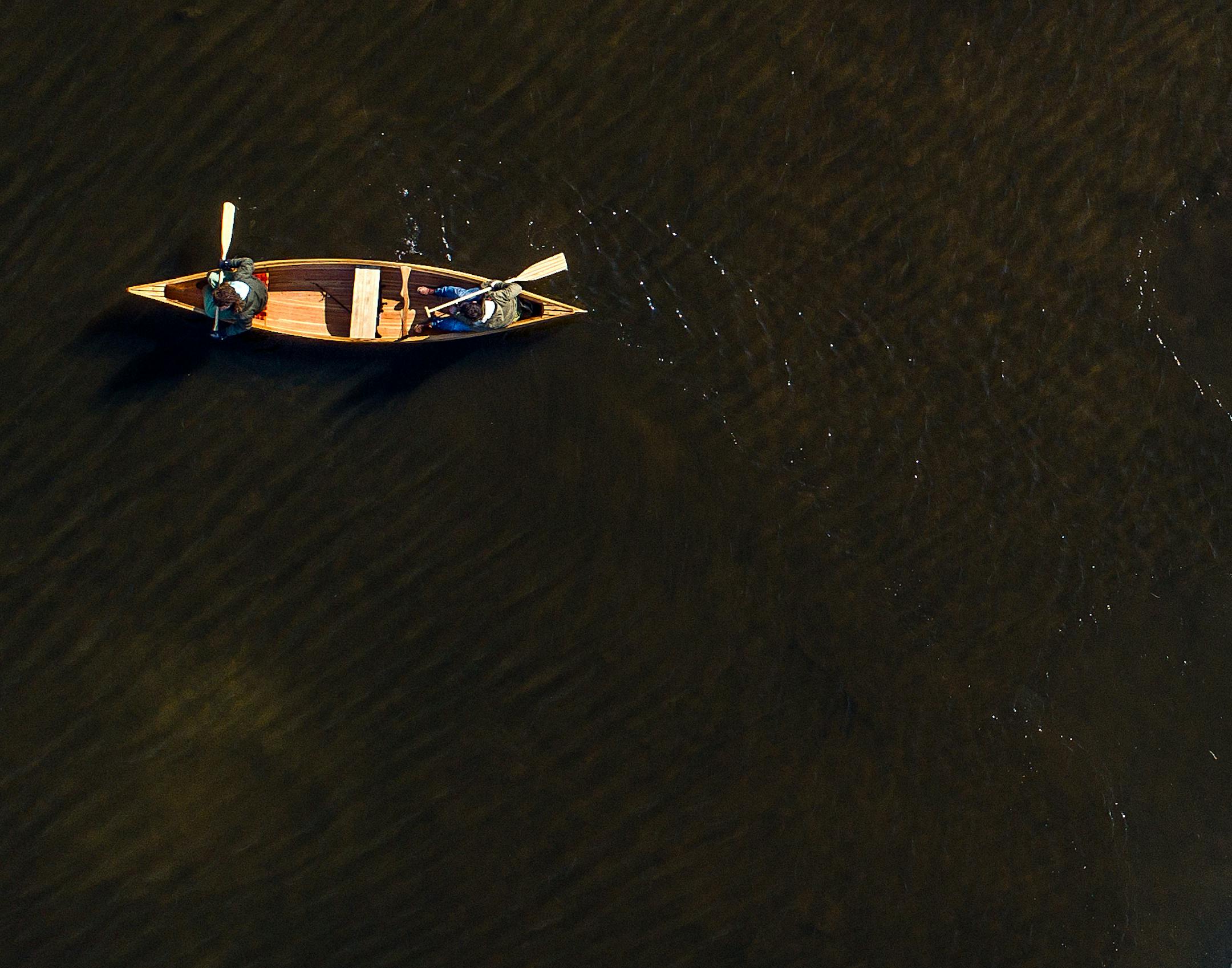 Two guys paddling in a canoe in the winter season. High above shot from a drone.