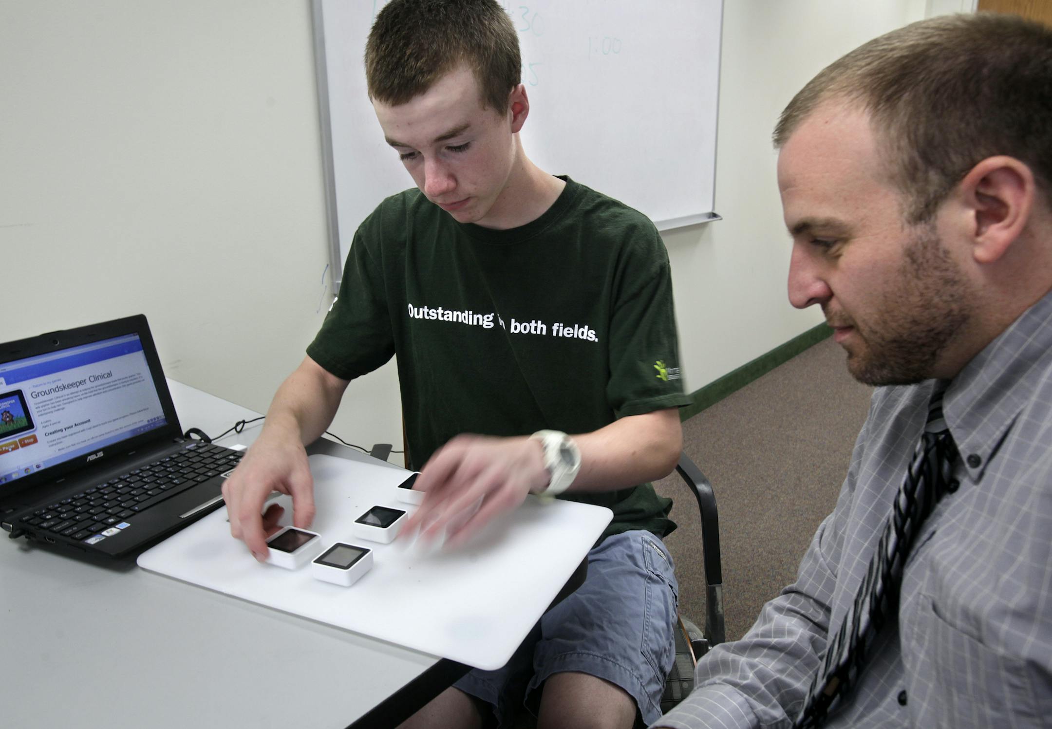 Noah Madson plays a game after Site Coordinator Kent Hranicka of CogCubed explained the rules of the game at Groves Academy in St. Louis Park, MN. CogCubed has attracted funding from Google for its video games that help diagnose disorders such as ADHD and autism. The company is partnering with Groves Academy, a school for children with learning disabilities, to see if the games can also improve cognitive function. A Groves student with ADHD, part of the CogCubed pilot study, will be playing the