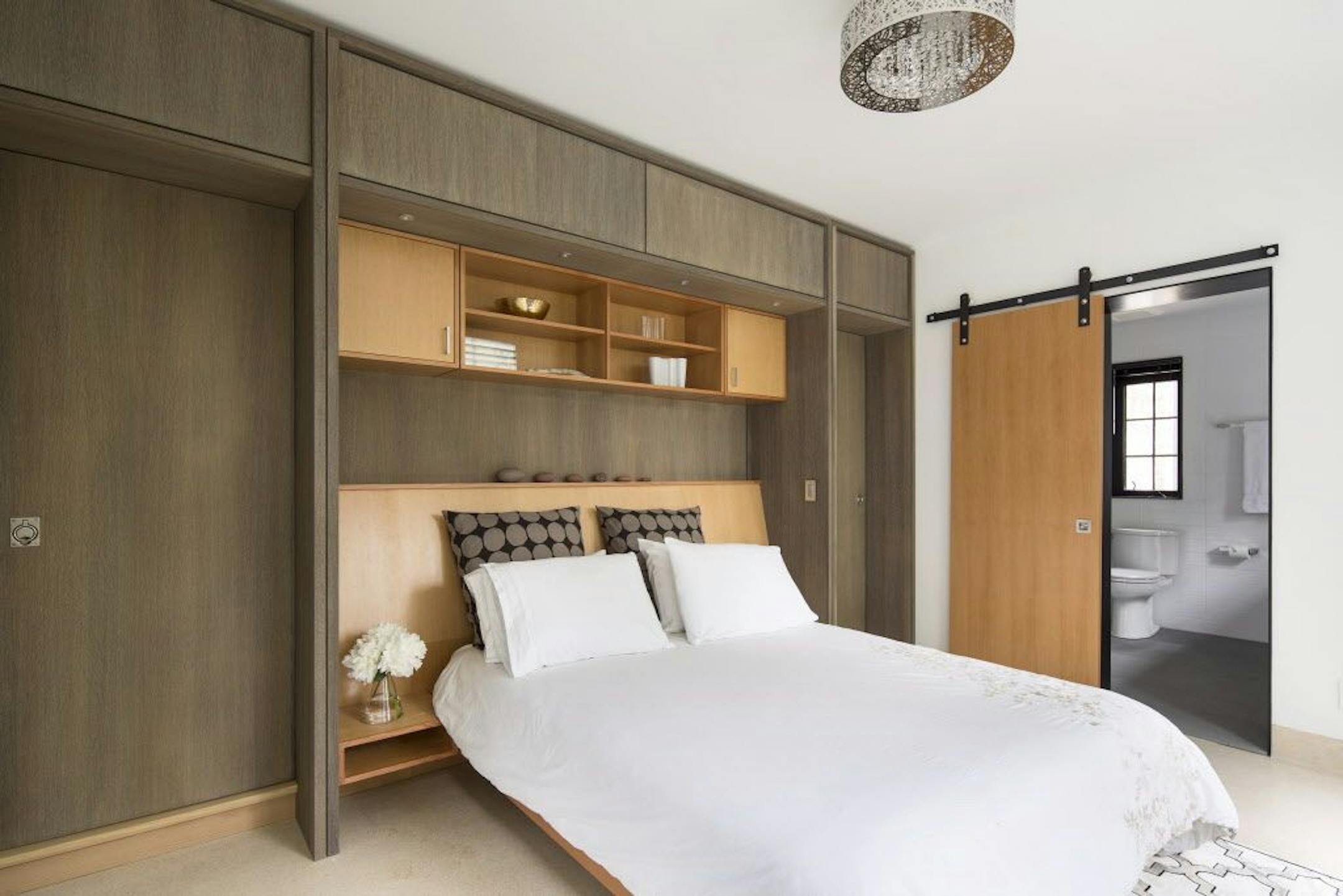 The pair of closet doors on each side of the bed "pocket and pivot" to keep everything out of sight.The remodeled bathroom is behind the sliding door.